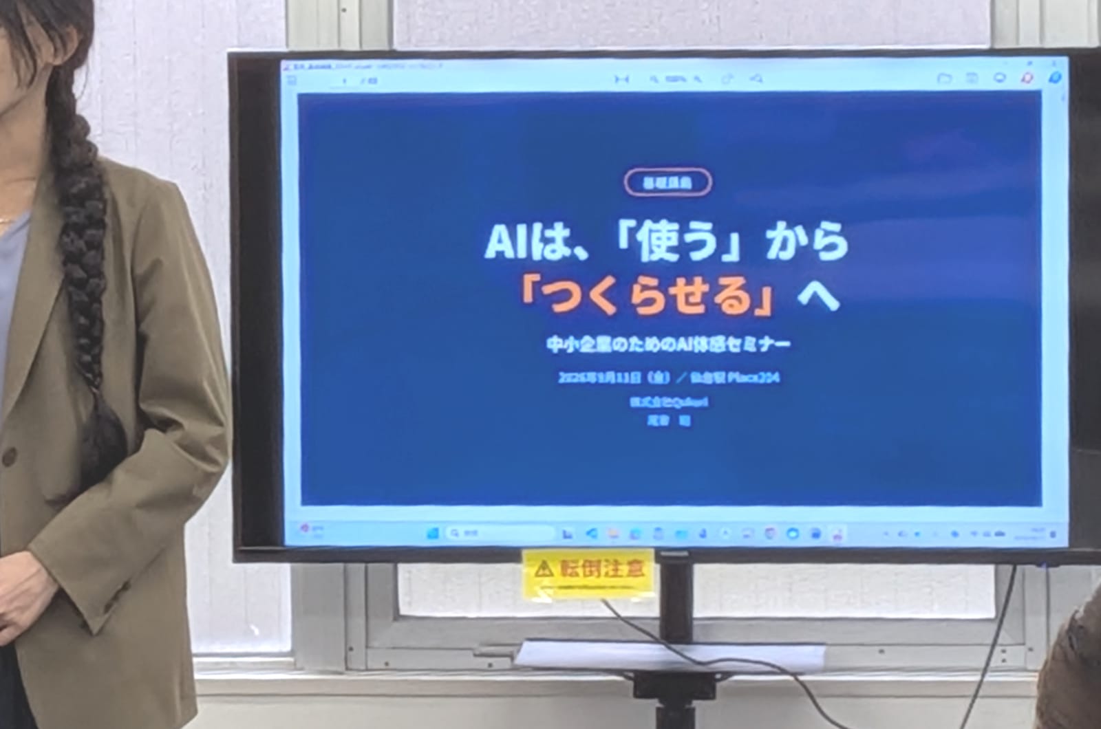 「AIは、『使う』から『つくらせる』へ」と映したモニターの横に立つ登壇者